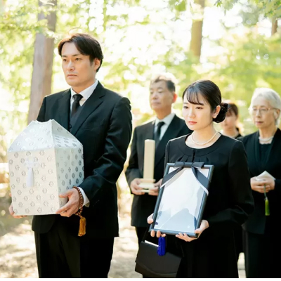 町田市の葬儀社であるファミリー福祉セレモニーの家族葬プランを象徴する、遺骨と遺影を抱えた家族のお見送り風景