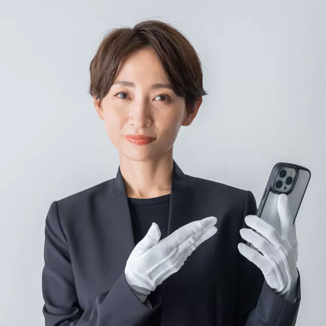 電話を手に持ち、案内をしているスーツ姿の女性葬儀社スタッフ